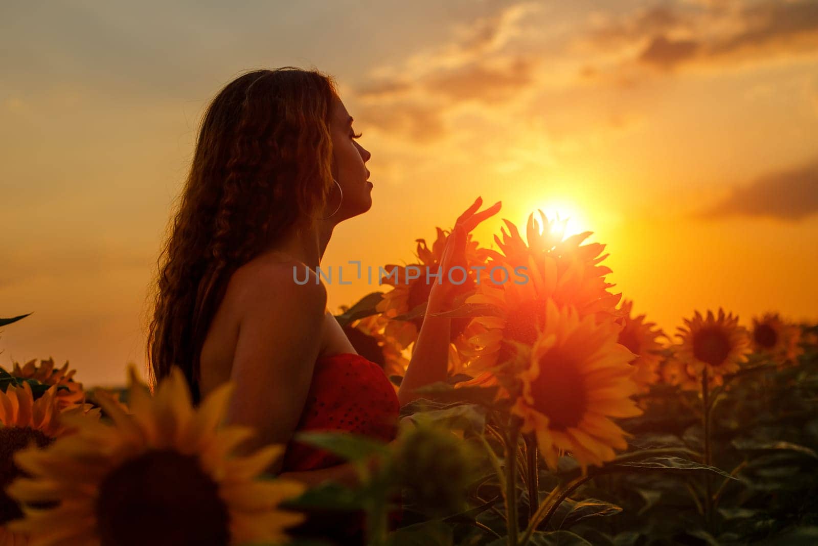 Young woman touches with her fingers a blooming sunflower by EkaterinaPereslavtseva
