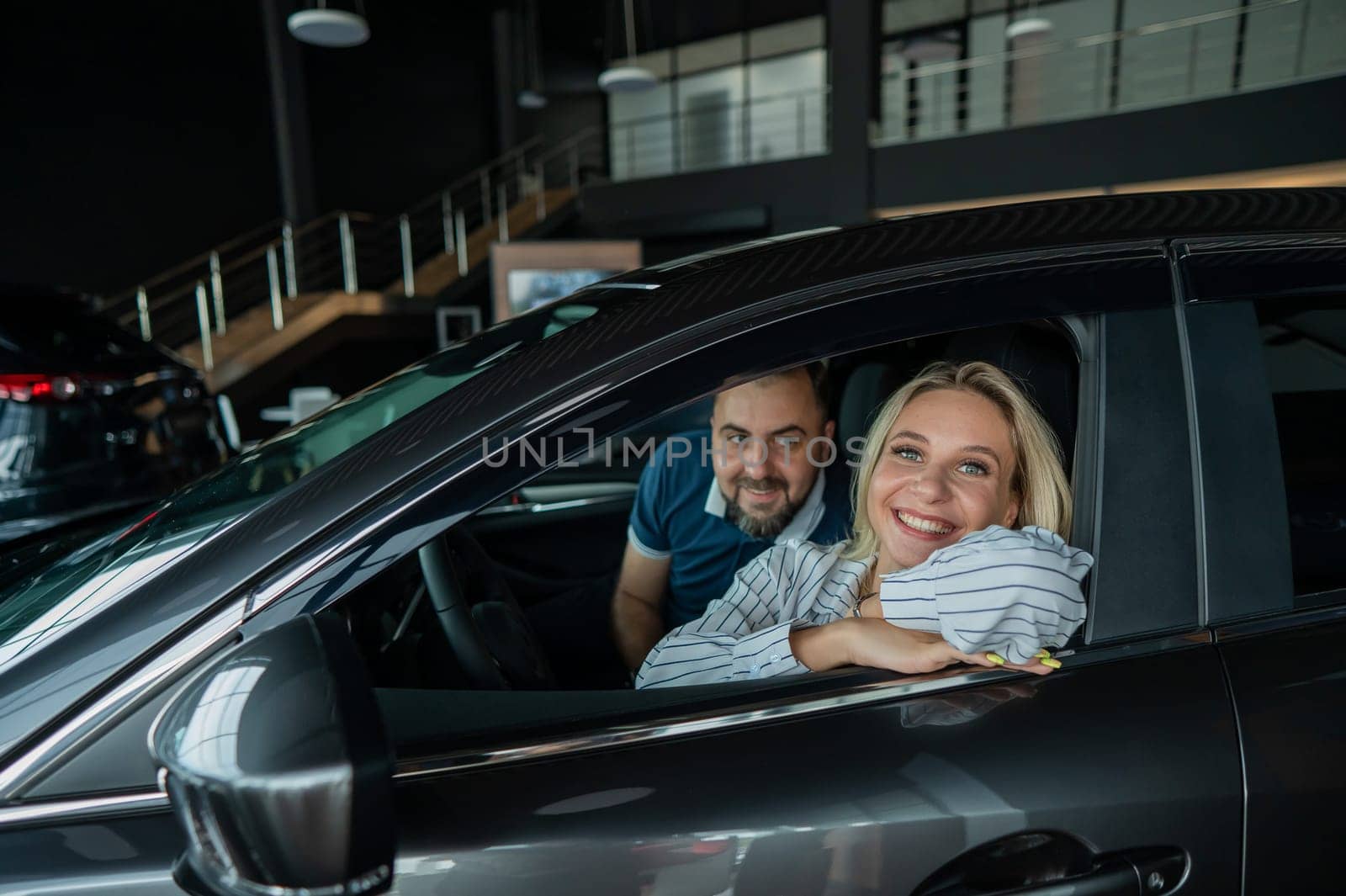 Happy caucasian couple is sitting in a new car in a car dealership. by mrwed54