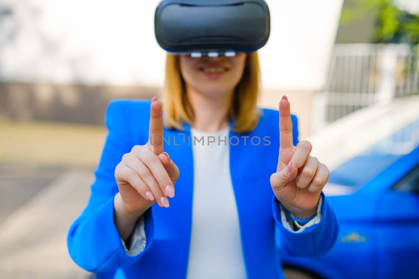 Business woman using VR goggles, moving her head touching the simulation screen with blue car on the background