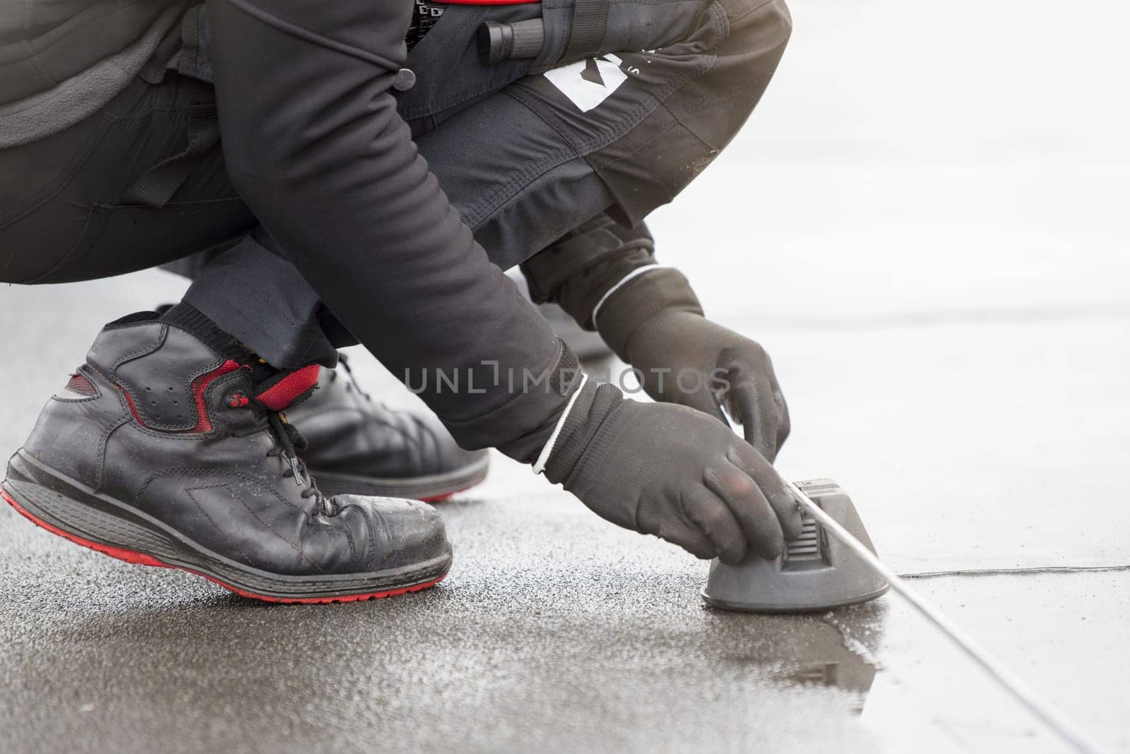 Ground wire. A worker lays a ground cable on the roof of a building. Electrician fixing aluminum wire for grounding solar panels by SERSOL