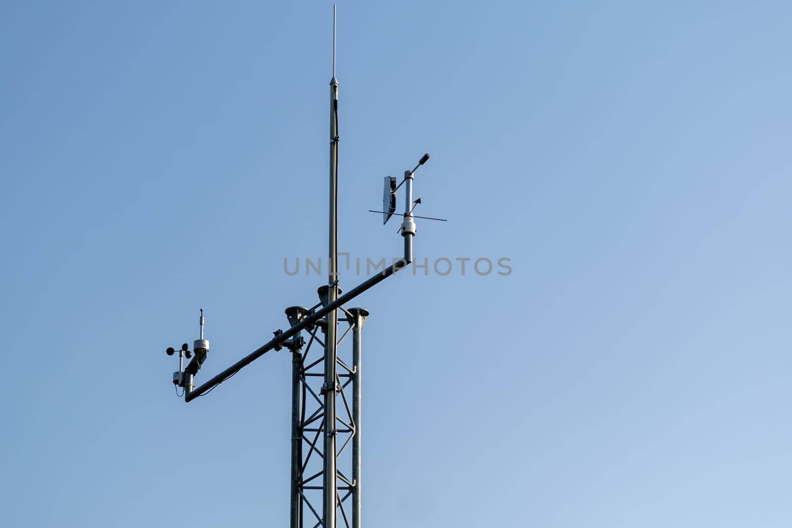 Communication antenna pole stands against clear blue sky. High antenna provides connection among relay cell service stations closeup
