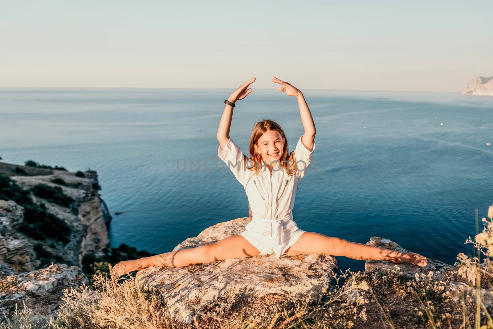 A beautiful teen girl is doing stretching exercise at the sea beach in summer sunny day.