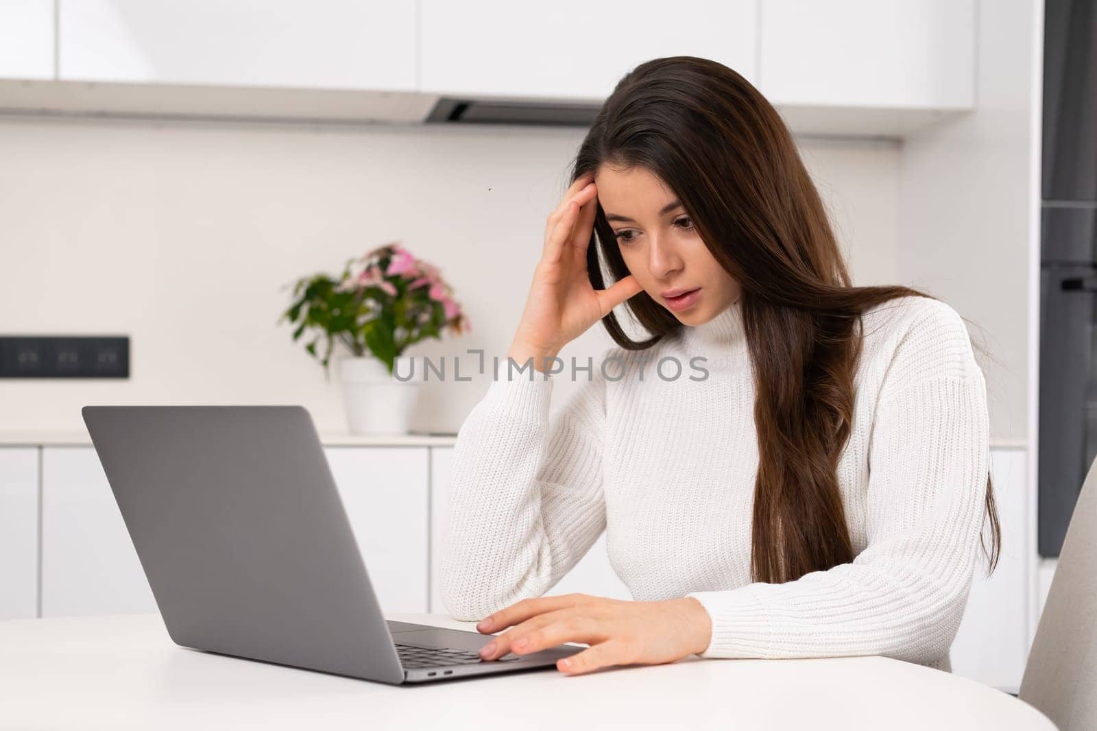 Stressed young woman thinks intensively while working at a computer at home by vladimka