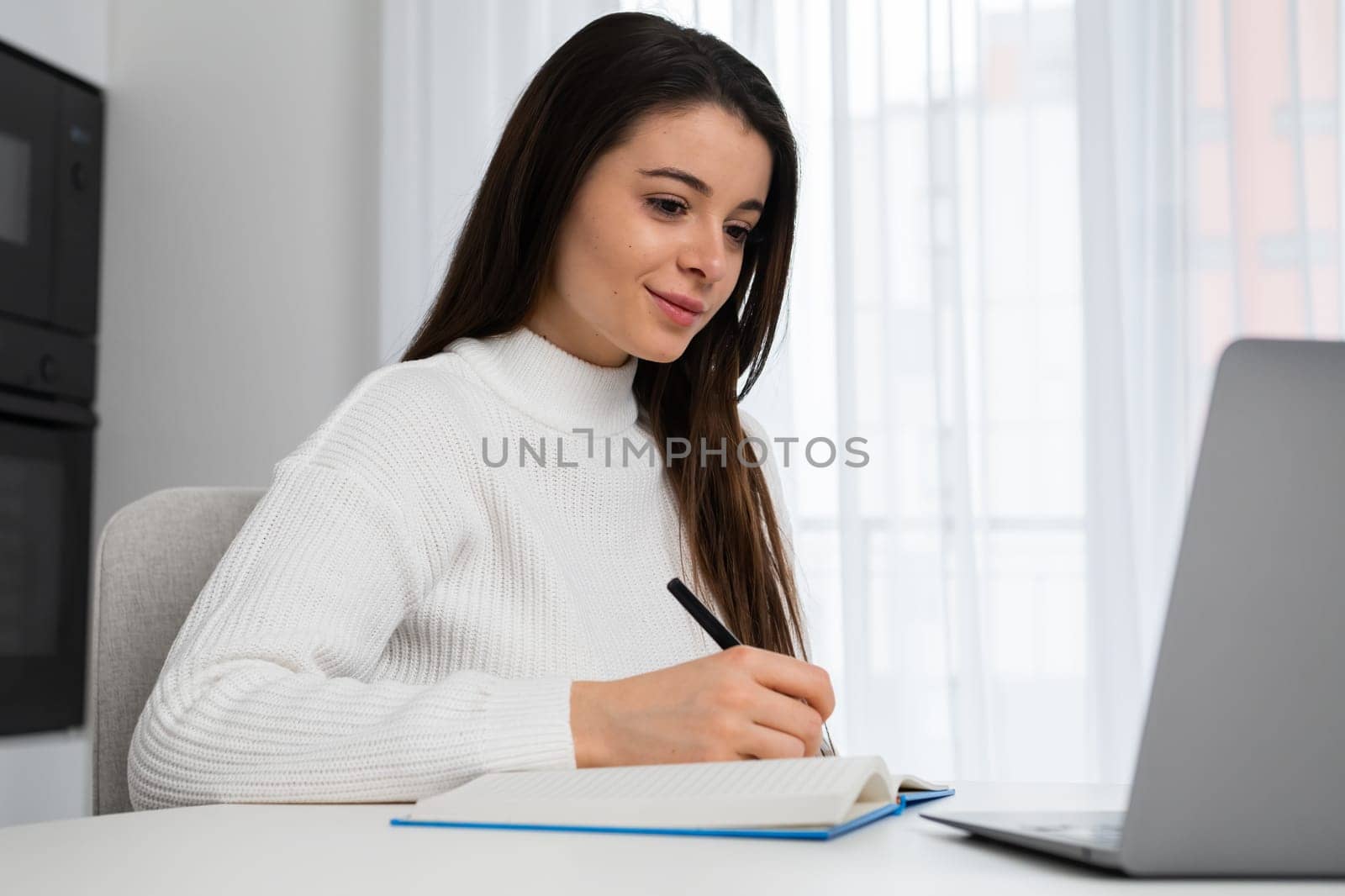 Focused young female college student preparing for exams and watching webinars by vladimka
