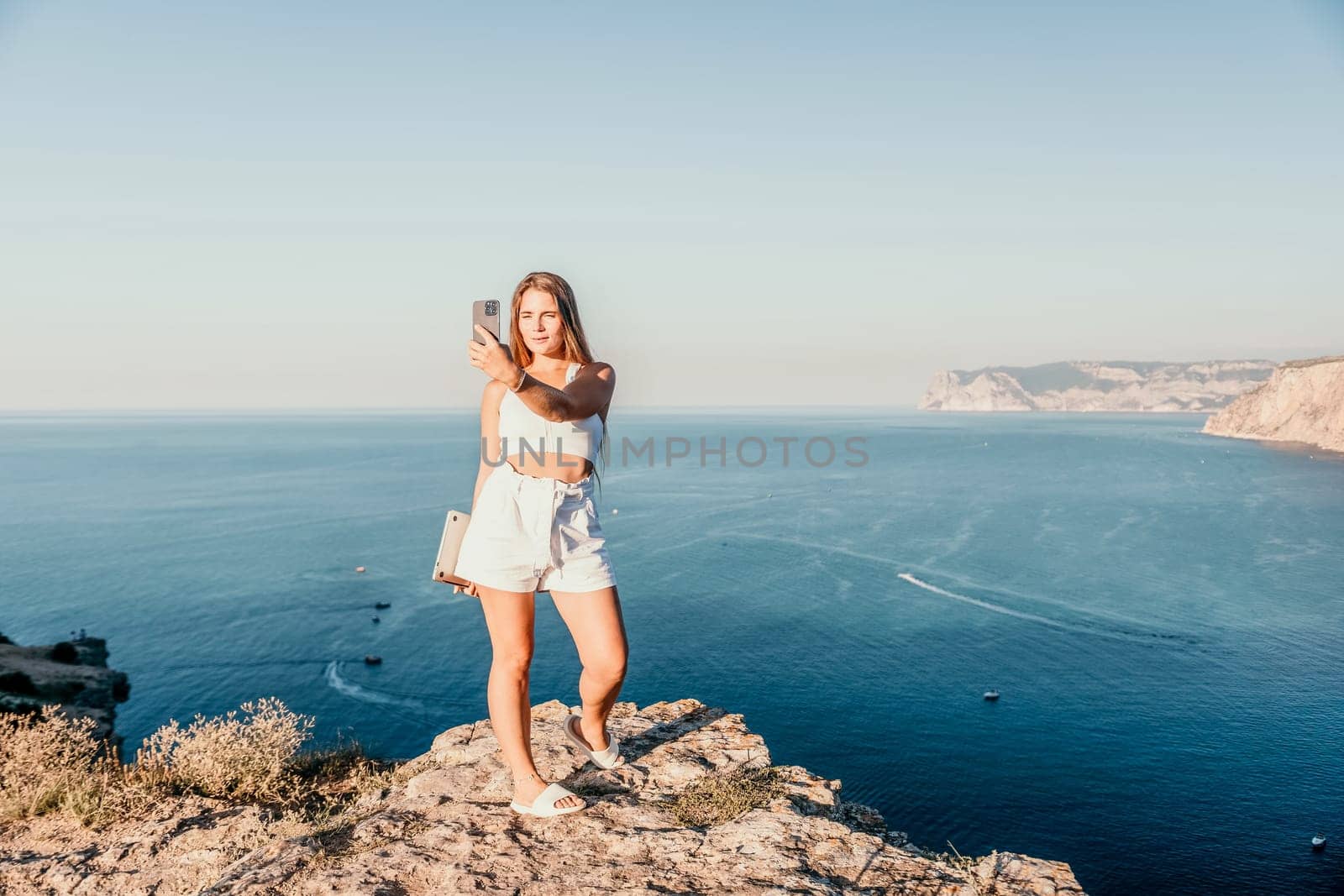 Woman travel sea. Young Happy woman in a long red dress posing on a beach near the sea on background of volcanic rocks, like in Iceland, sharing travel adventure journey