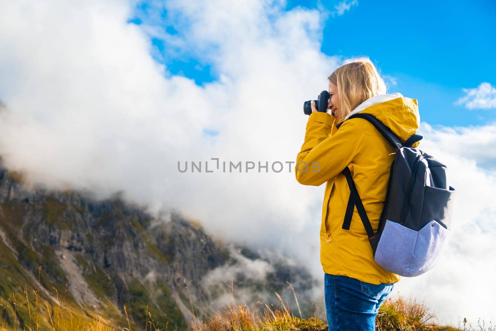 Nature photographer taking pictures during a hiking in Pass Giau in Italy against blue sky. Travel and wanderlust concept.