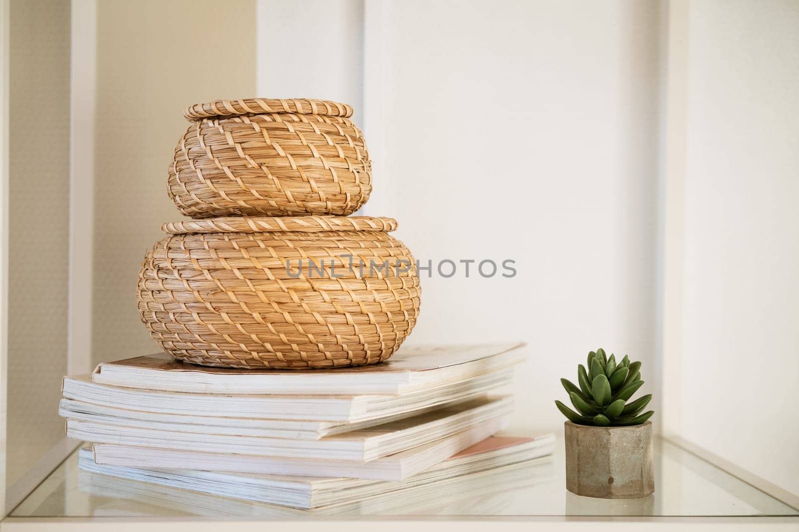 Close-up of a round straw box with a lid on a white shelf. by EkaterinaPereslavtseva