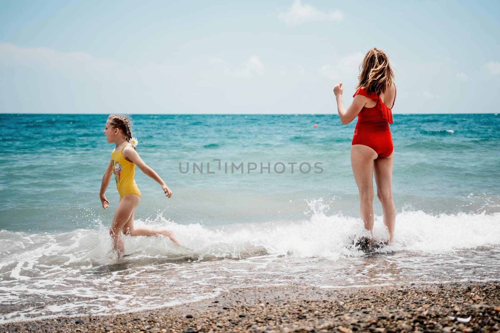 Happy loving family mother and daughter having fun together on the beach. Mum playing with her kid in holiday vacation next to the ocean - Family lifestyle and love concept.