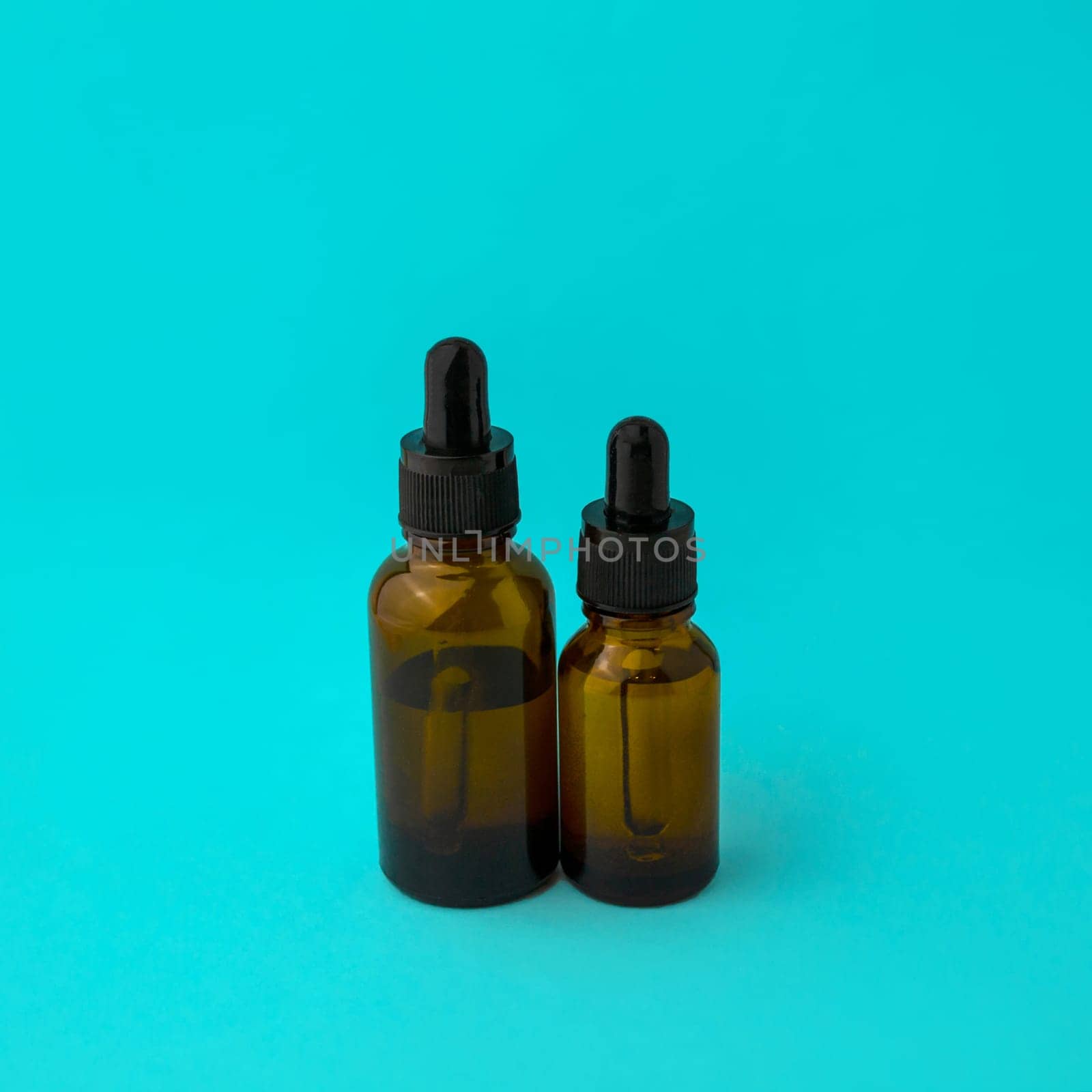 Glass vials with a pipette on a blue background. Brown glass vials with a pipette on a blue background.