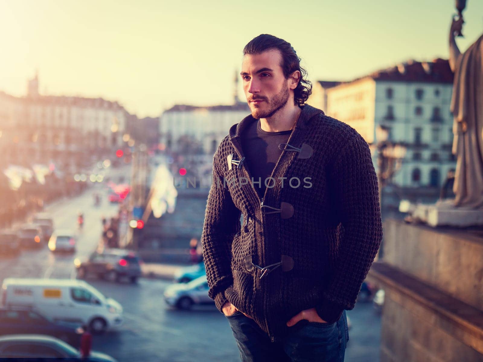 One handsome young man in urban setting in European city, Turin in Italy, standing and looking away