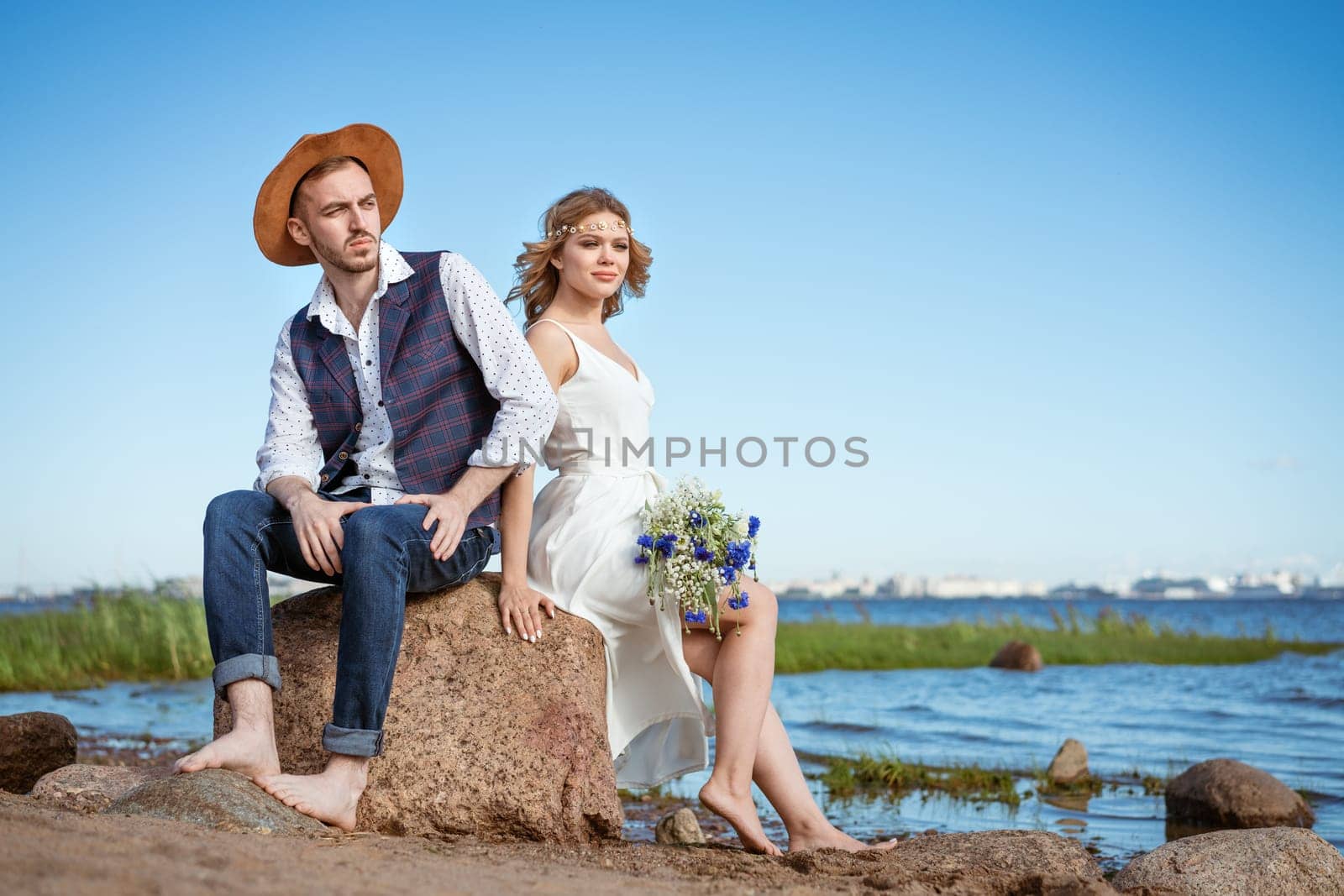 happy caucasian couple man and woman on the beach, summer day holding a bouquet of flowers in her hand