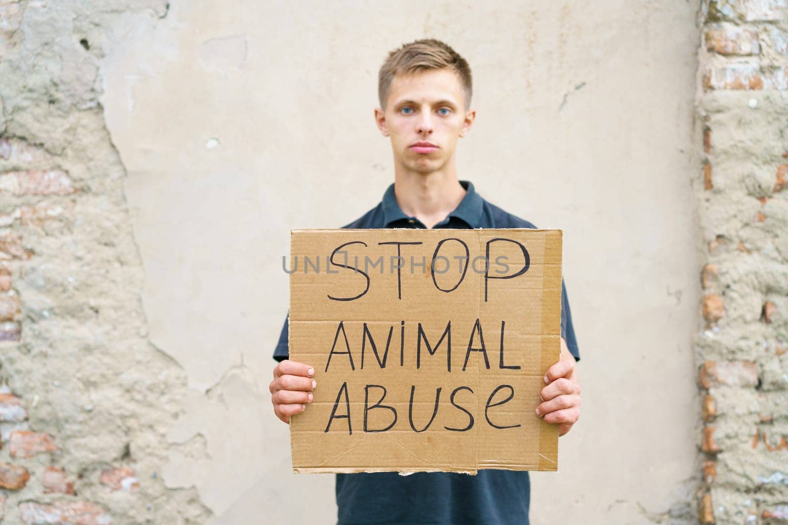 Stop animal abuse guy holding a cardboard box with the inscription. Animal activist. Caucasian young man stands in protest against animal bullying