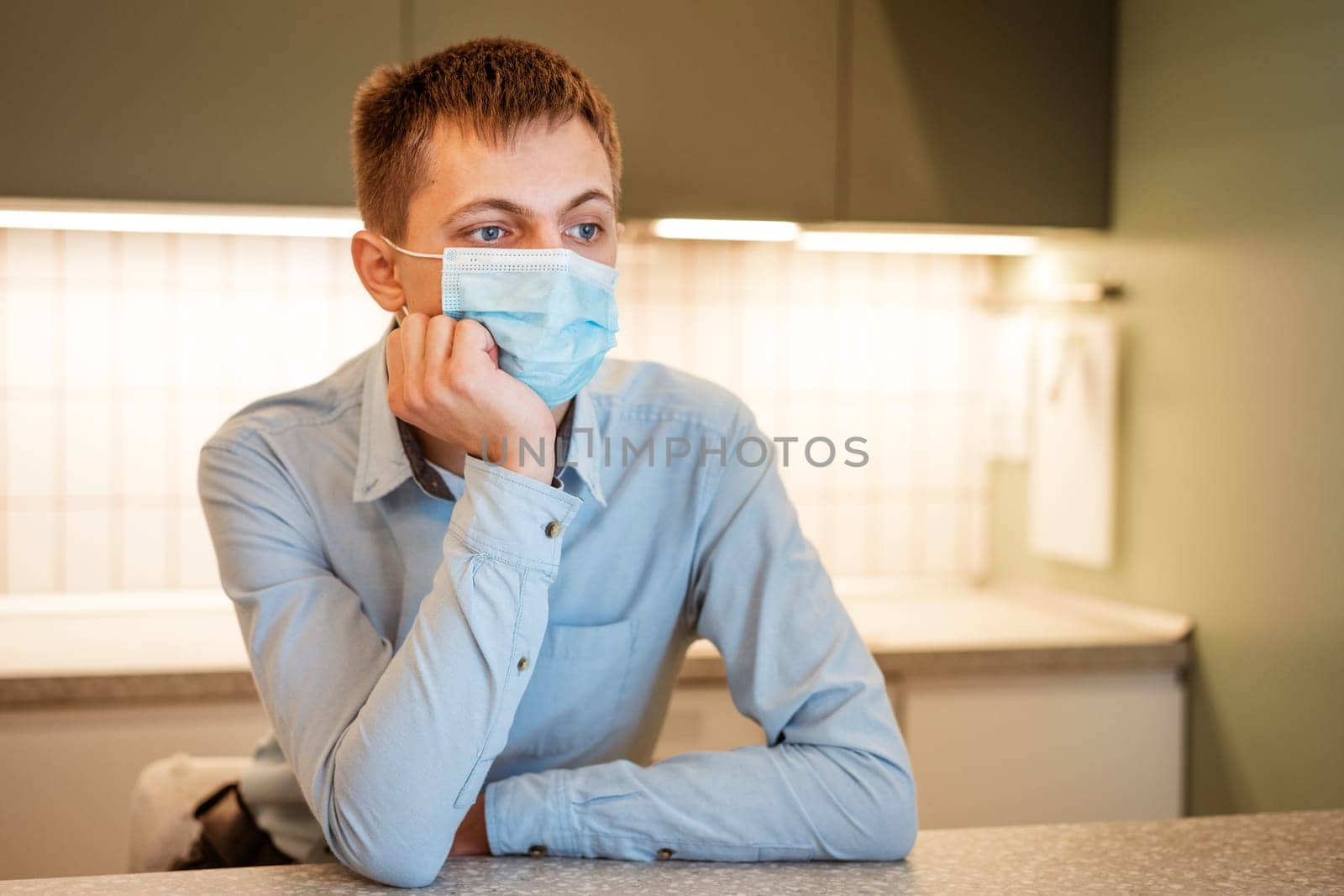 young guy sits in a shirt and a mask in the kitchen by EkaterinaPereslavtseva