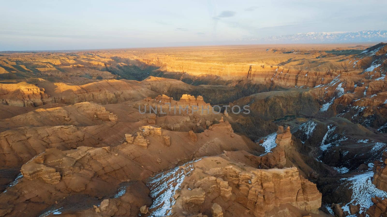 Charyn Grand Canyon with orange rock walls. Aerial view from the drone of the steep canyon walls, cracks and tunnels. There is snow in places. Beautiful sunset and sunrise. Brother of the Grand Canyon