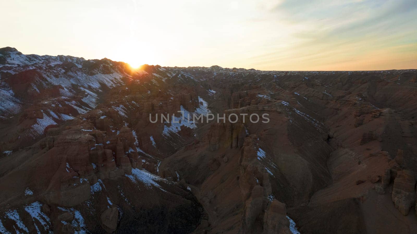 Charyn Grand Canyon with orange rock walls. Aerial view from the drone of the steep canyon walls, cracks and tunnels. There is snow in places. Beautiful sunset and sunrise. Brother of the Grand Canyon