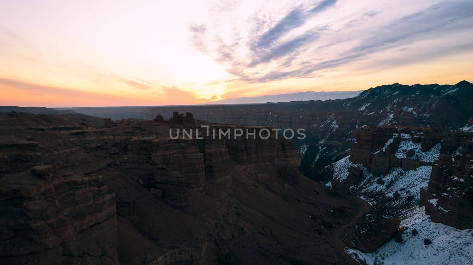 Charyn Grand Canyon with orange rock walls. Aerial view from the drone of the steep canyon walls, cracks and tunnels. There is snow in places. Beautiful sunset and sunrise. Brother of the Grand Canyon
