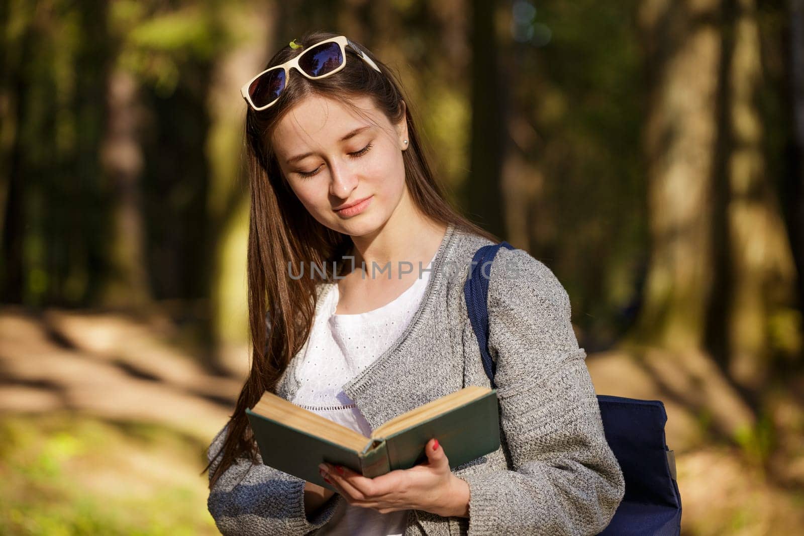 Young caucasian woman in the park reading a book on a spring sunny day,