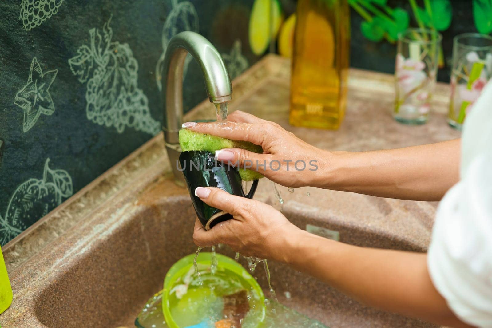 Woman washing dirty dishes in the sink close-up. Female hands cleaning dirty dishes after dinner