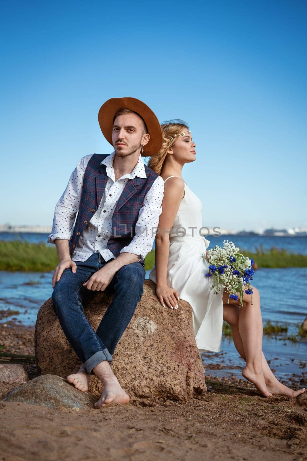 happy caucasian couple man and woman on the beach, summer day holding a bouquet of flowers in her hand