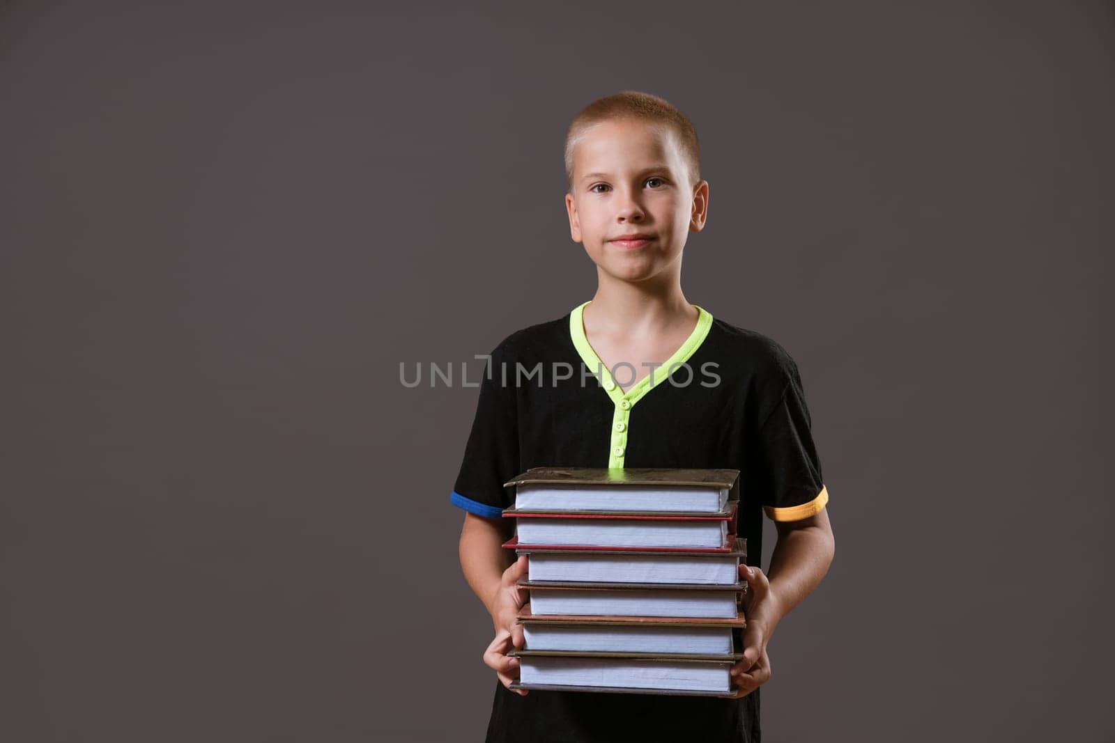 schoolboy boy holding a stack of books on a gray background by EkaterinaPereslavtseva