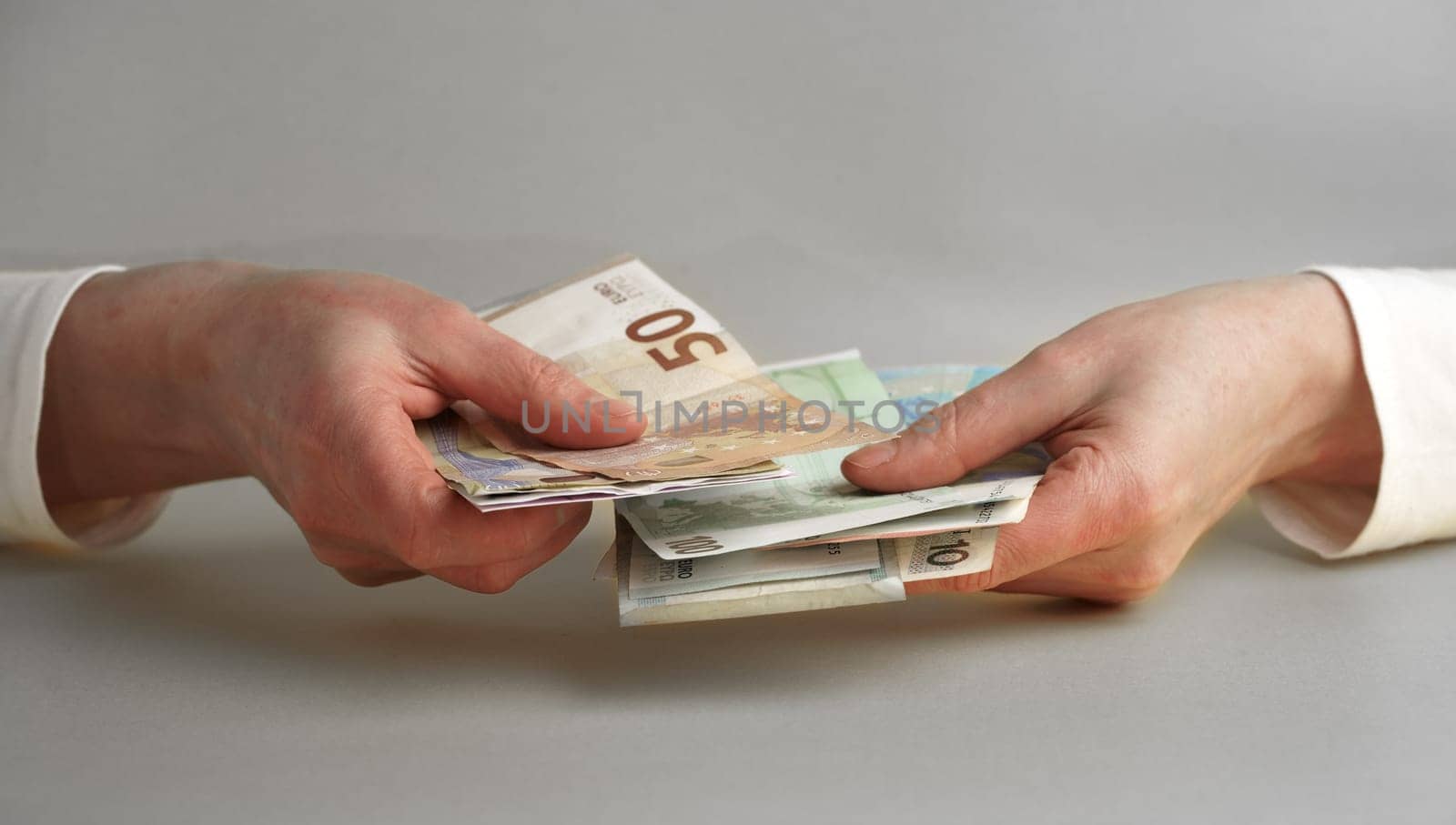 Hands and money. Women's hands hold, count money in euros and dollars isolated on a gray background