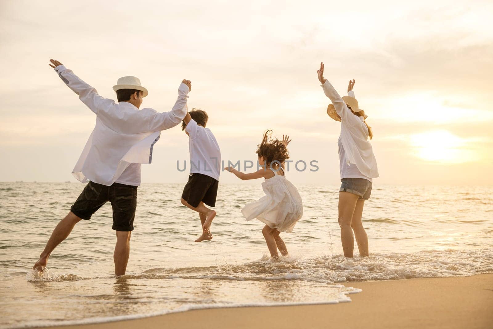 Happy Asian family have fun jumping together on beach in holiday at sunset time by Sorapop