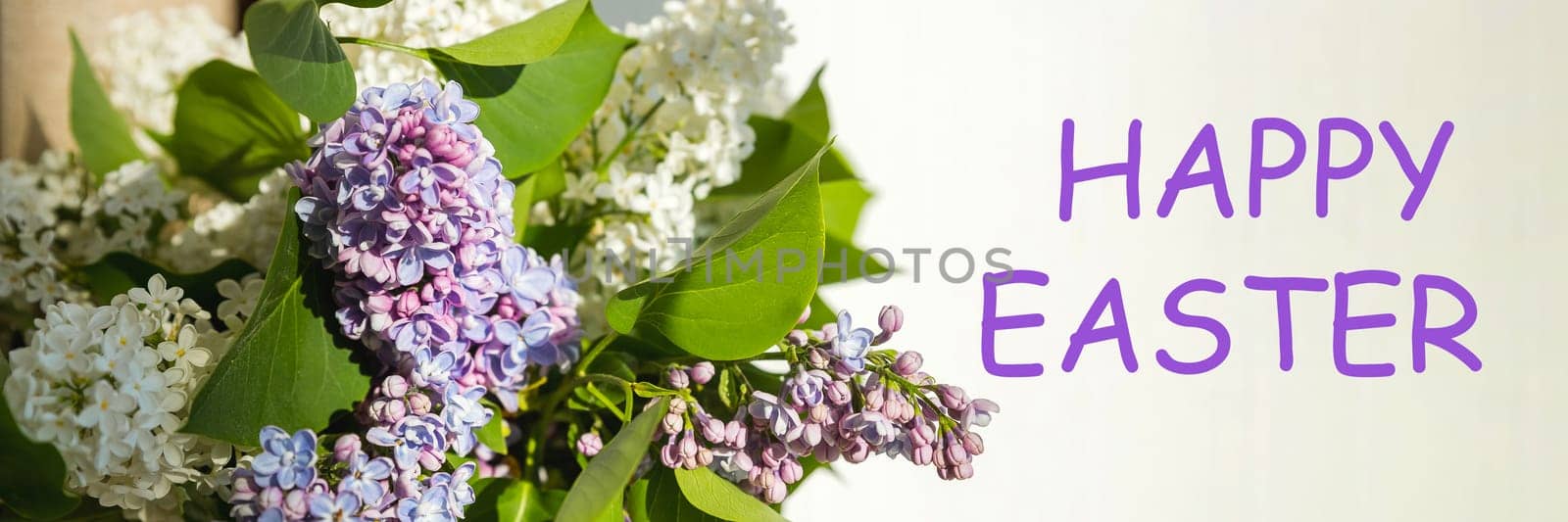 happy easter text sign. greeting card. spring flat lay. purple lilac flowers on white background