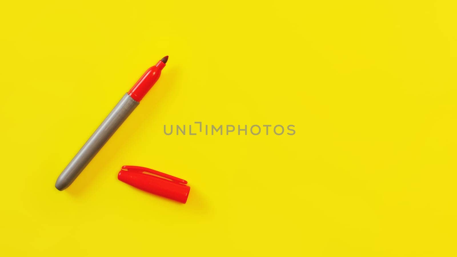 Top view on red marker, cap opened, on yellow board, copyspace for your text on right side.