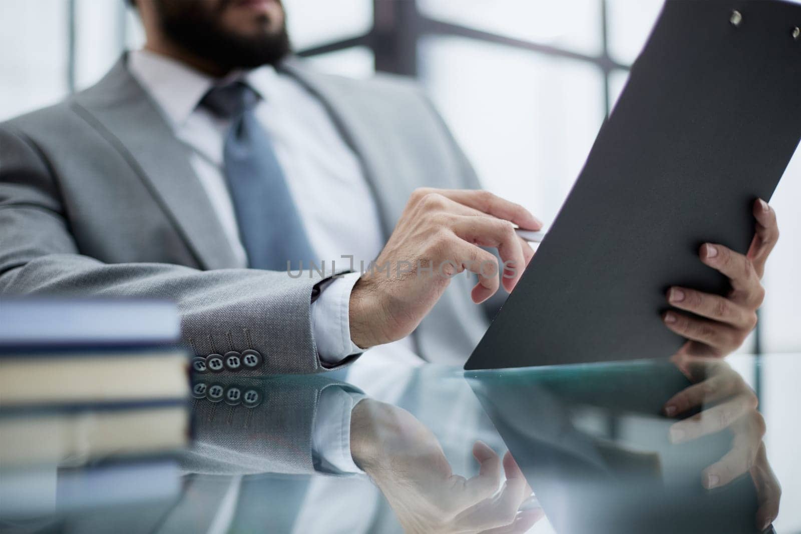 Businessman sitting at office desk signing a contract with shallow focus on signature