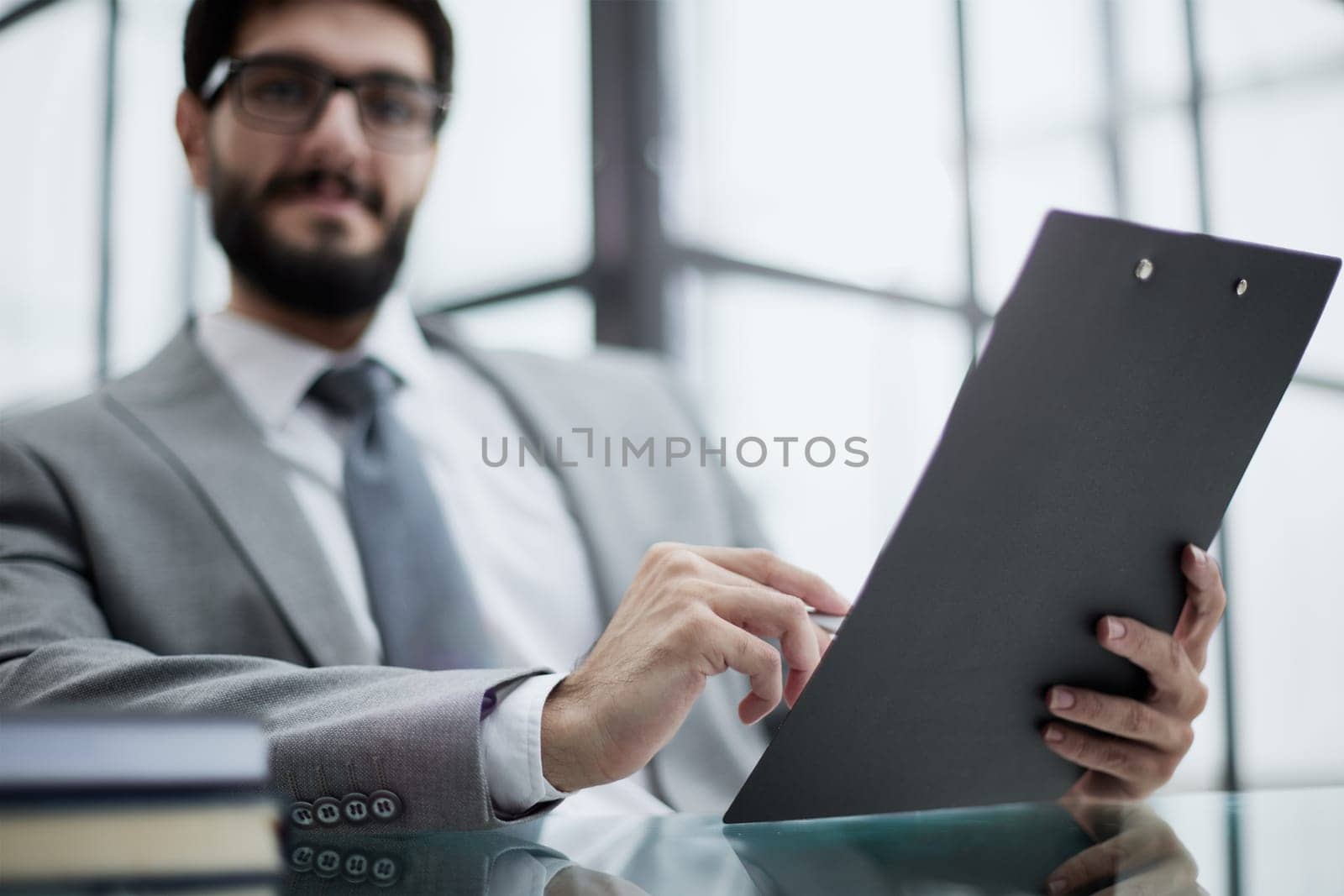 Businessman sitting at office desk signing a contract with shallow focus on signature