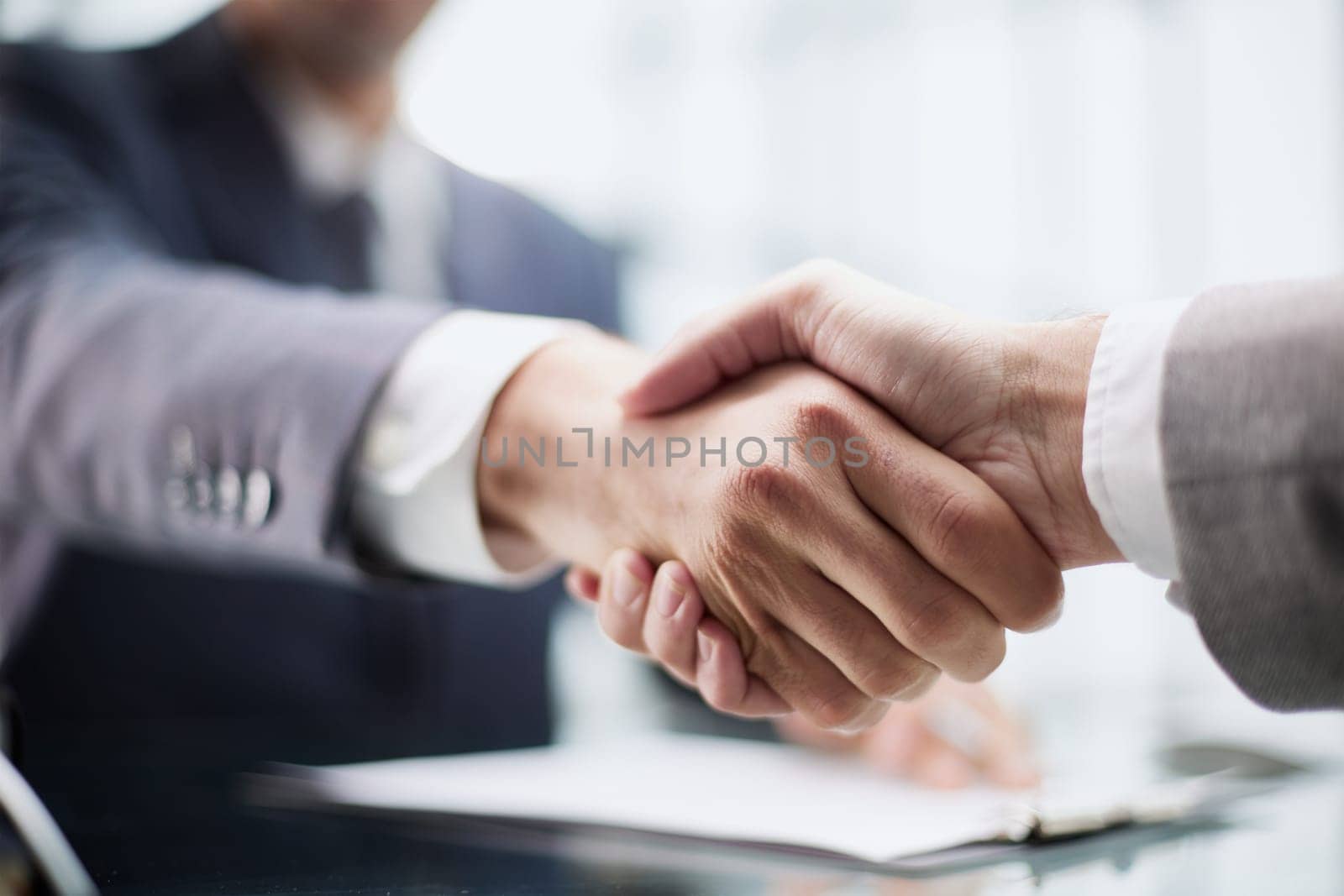 Photo of business handshake over workplace in office