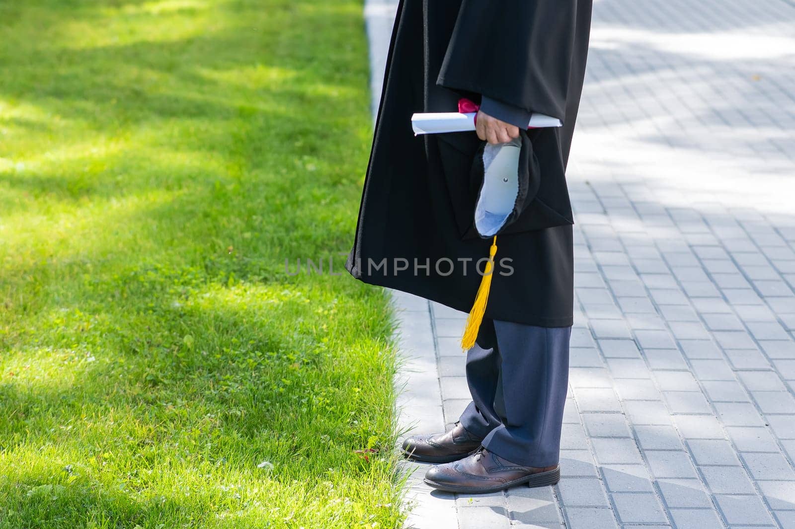 Close-up of male hands holding diploma and graduation cap. by mrwed54