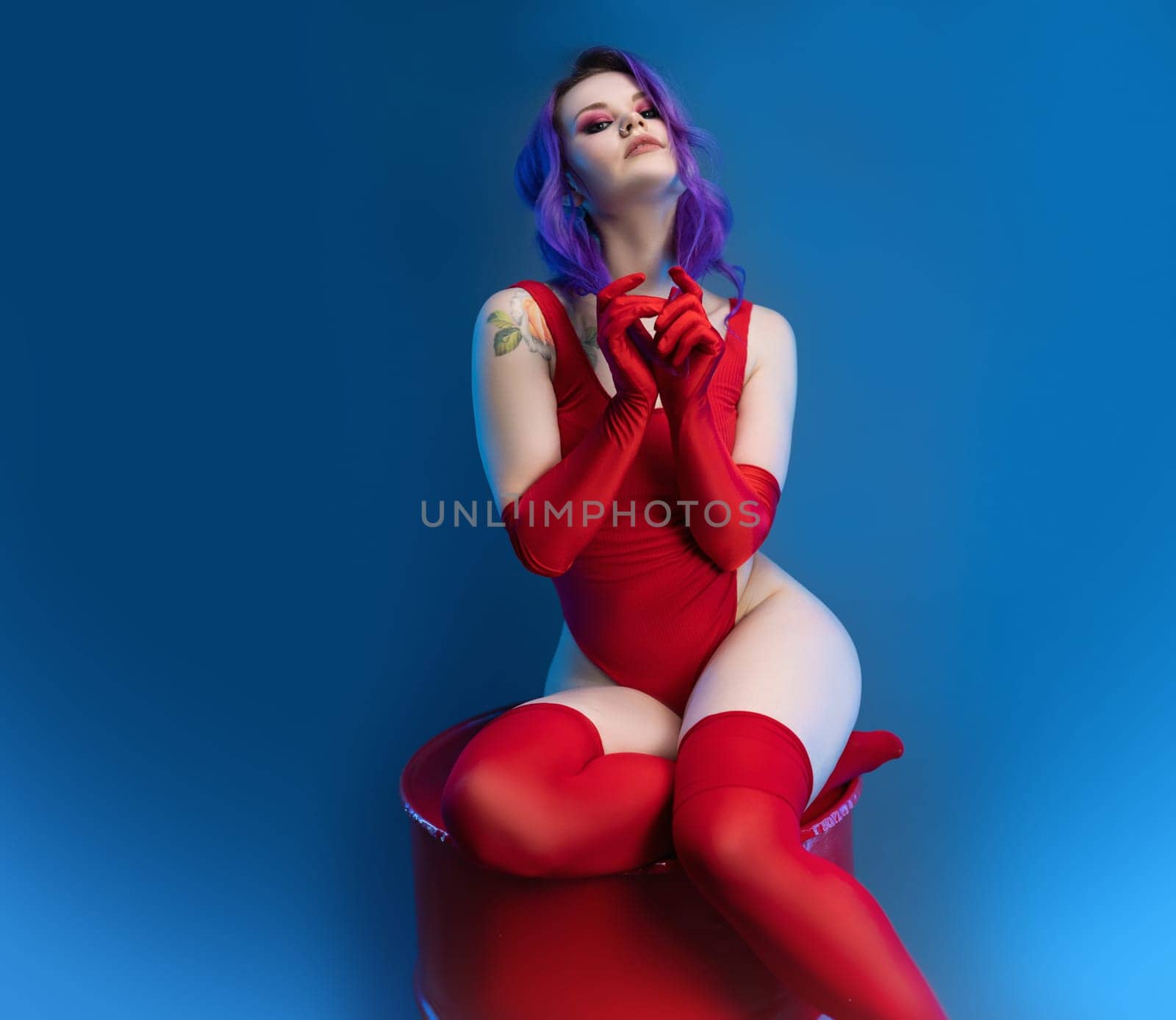 the sexy girl in red bodysuit stockings and red gloves poses erotically against the background