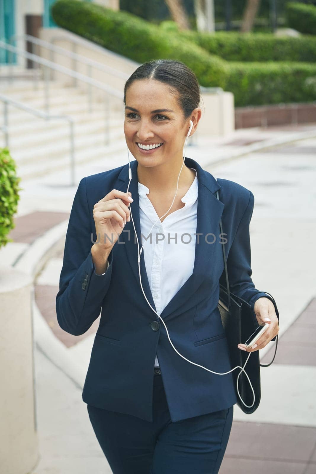 Handsfree communication for a busy woman on the move. a young businesswoman her phone and earphones while out in the city