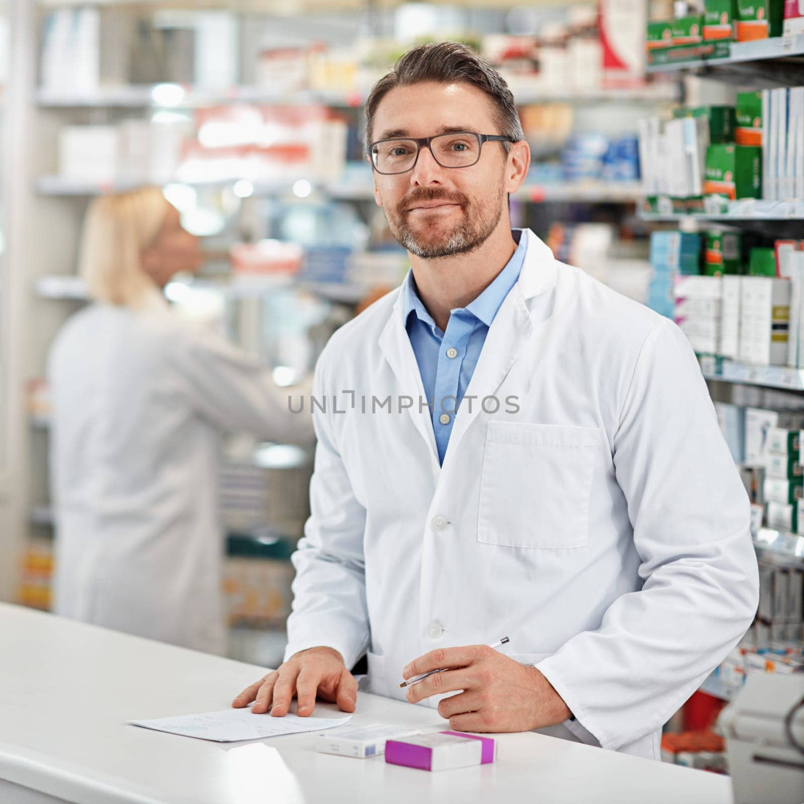 Drop in anytime to see me without an appoinymrmt. a pharmacist at work with his colleague in the background. All products have been altered to be void of copyright infringements. by YuriArcurs