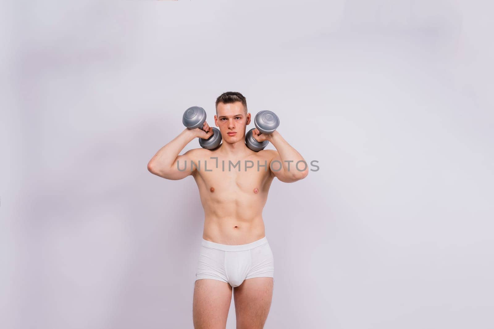 Shirtless bodybuilder holding dumbell and showing his muscular arms. by Zelenin