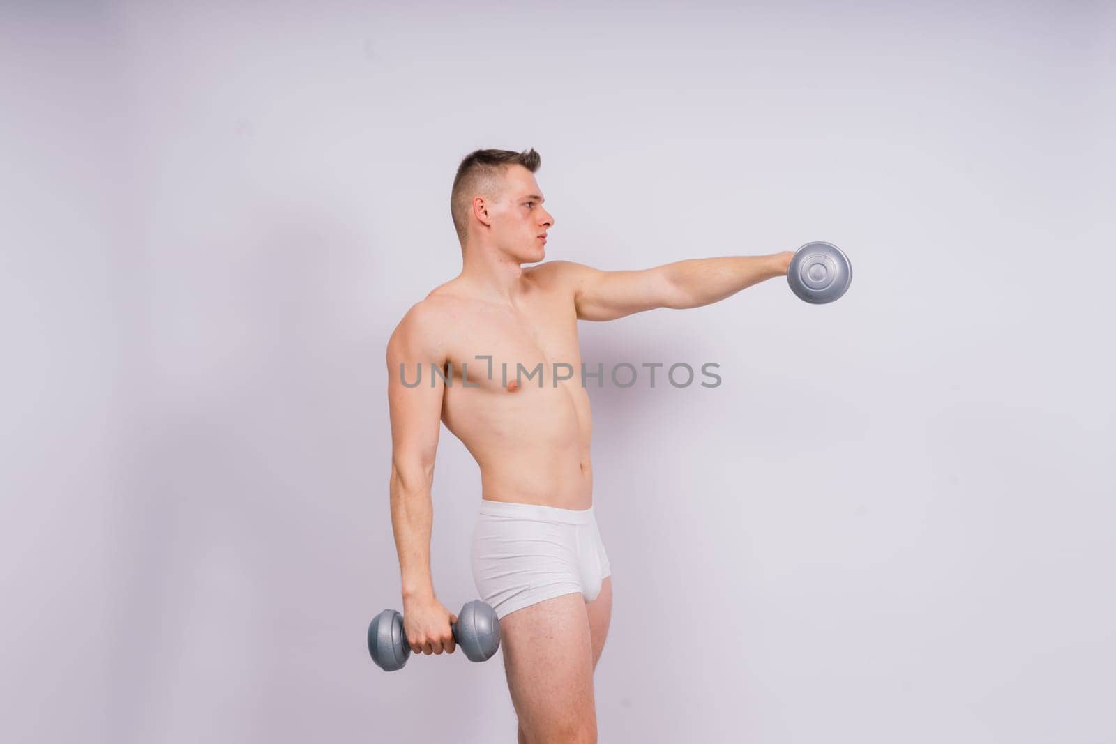 Shirtless bodybuilder holding dumbell and showing his muscular arms. by Zelenin