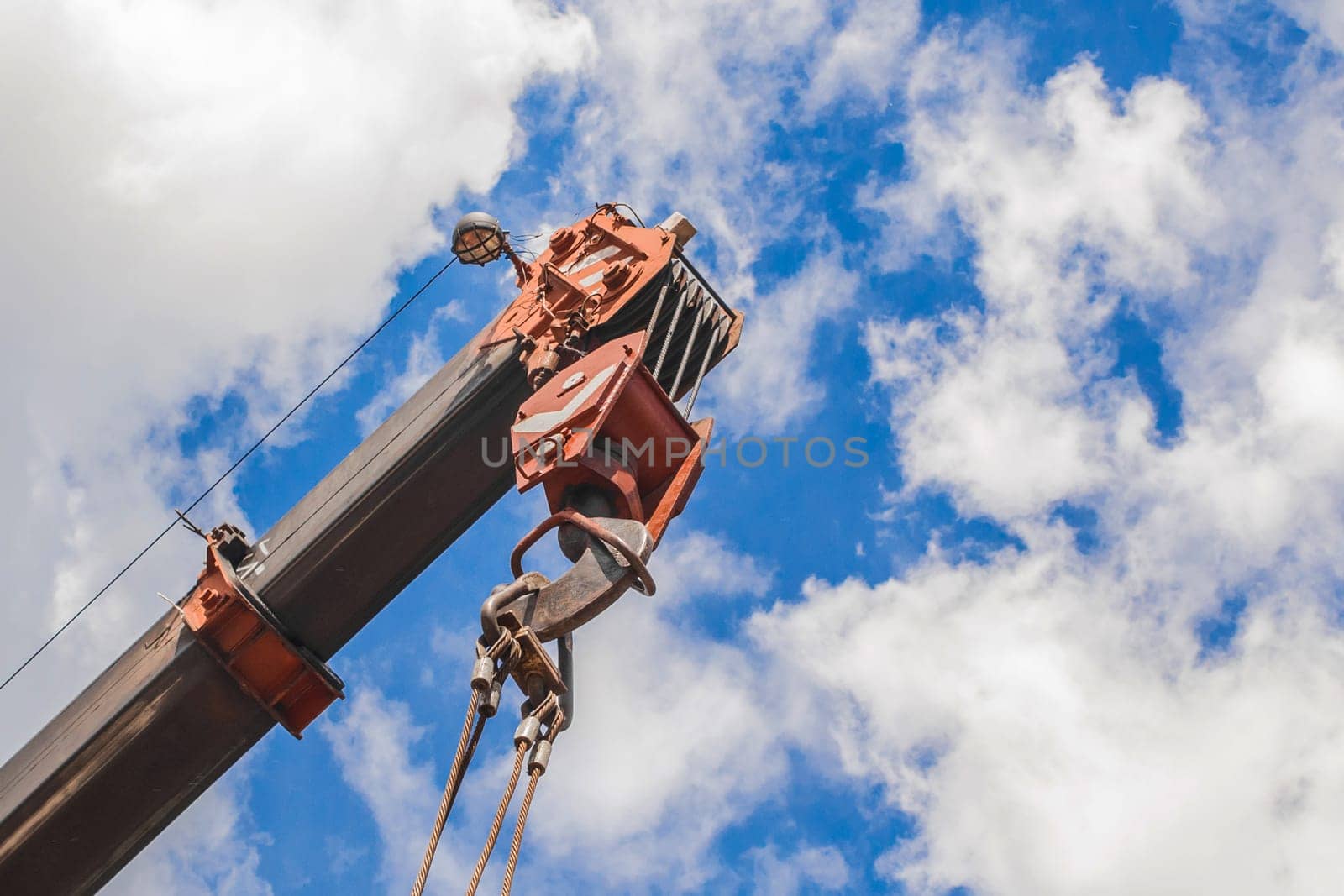 Lifting hoisting mechanism with rope steel of the machine bridge crane with iron cable and hook on a blue sky background.