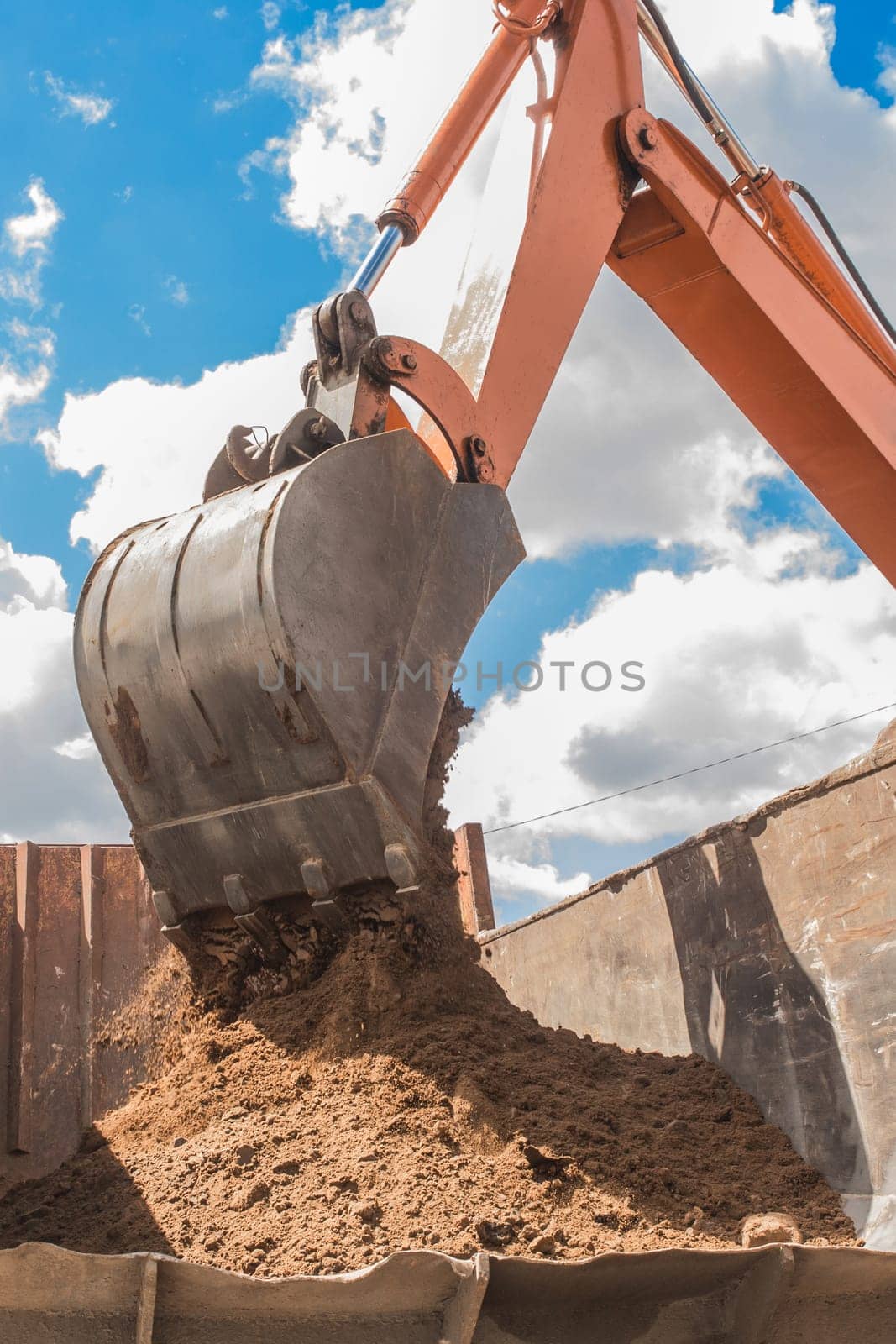 Excavation works. The bucket of the tractor loads the soil ground with a heavy shovel into the back of a dump truck on the construction site by AYDO8