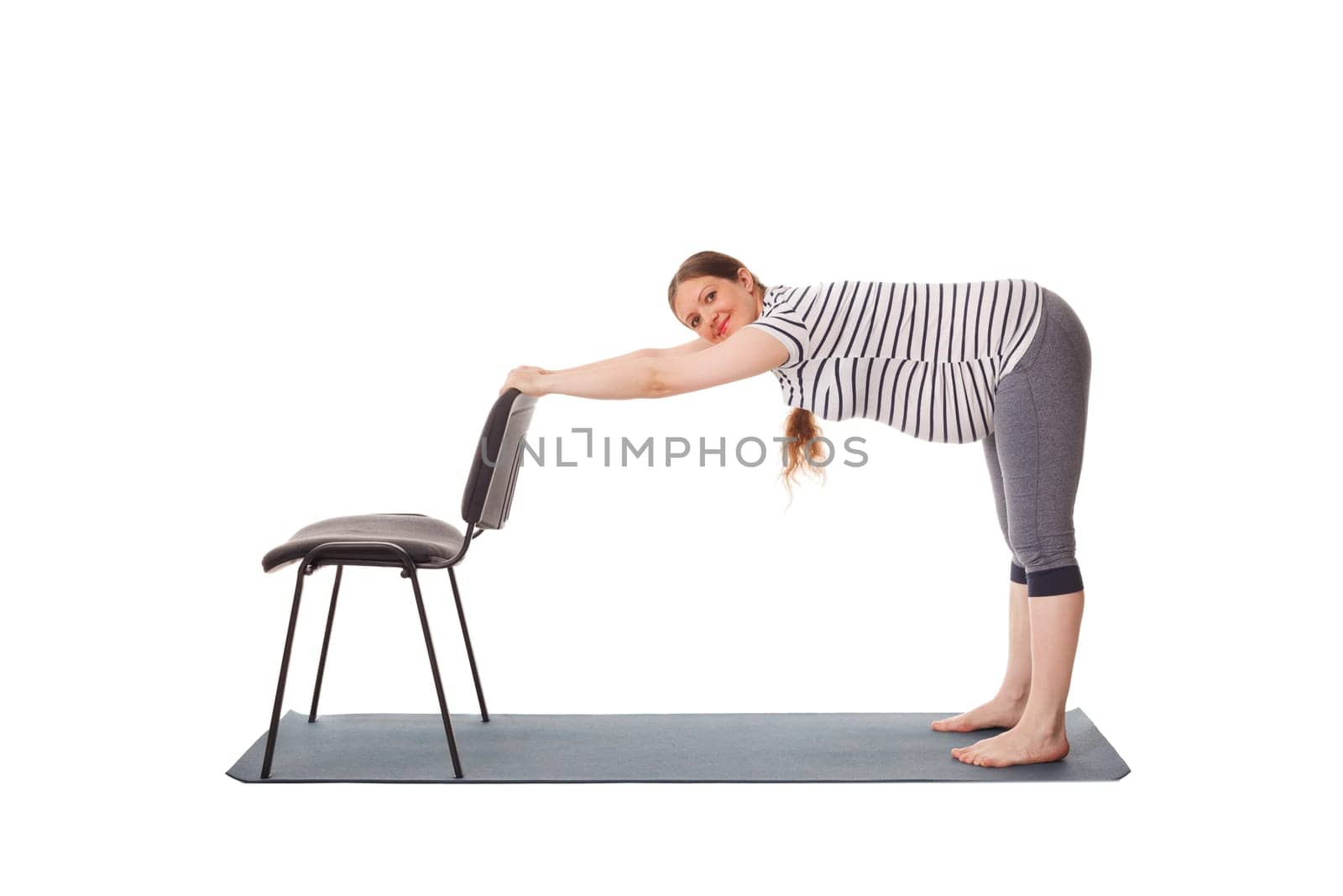 Pregnant woman doing yoga asana Uttanasana isolated by dimol