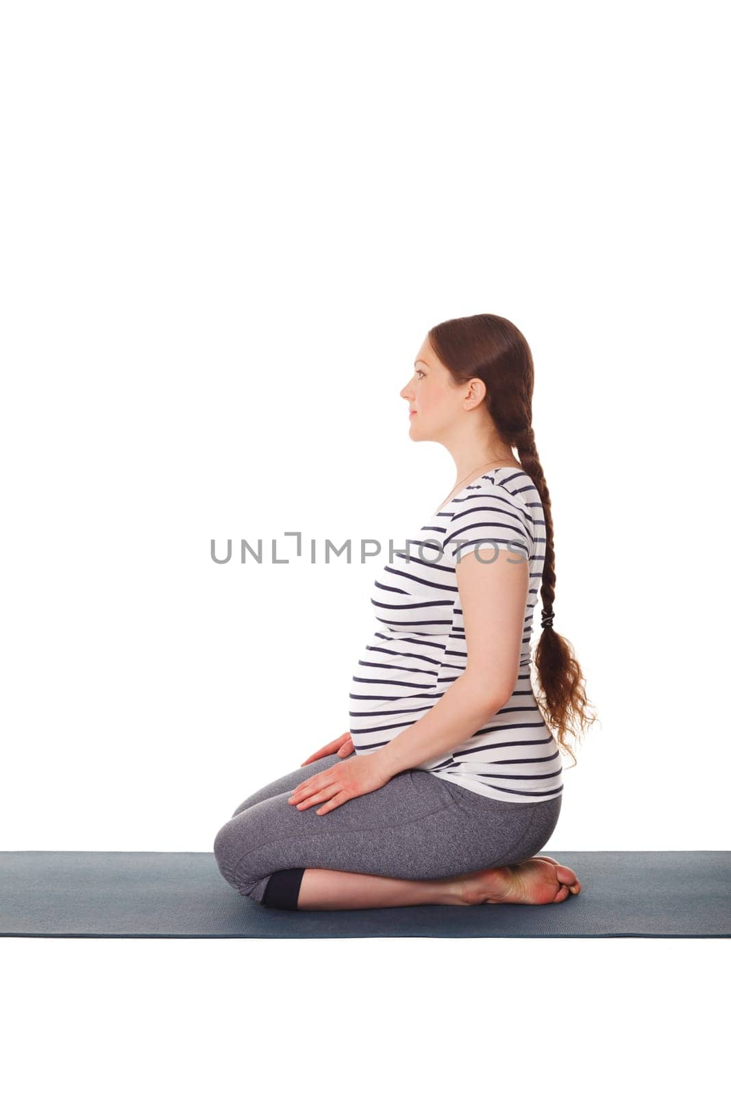 Pregnant woman doing yoga asana Virasana isolated by dimol