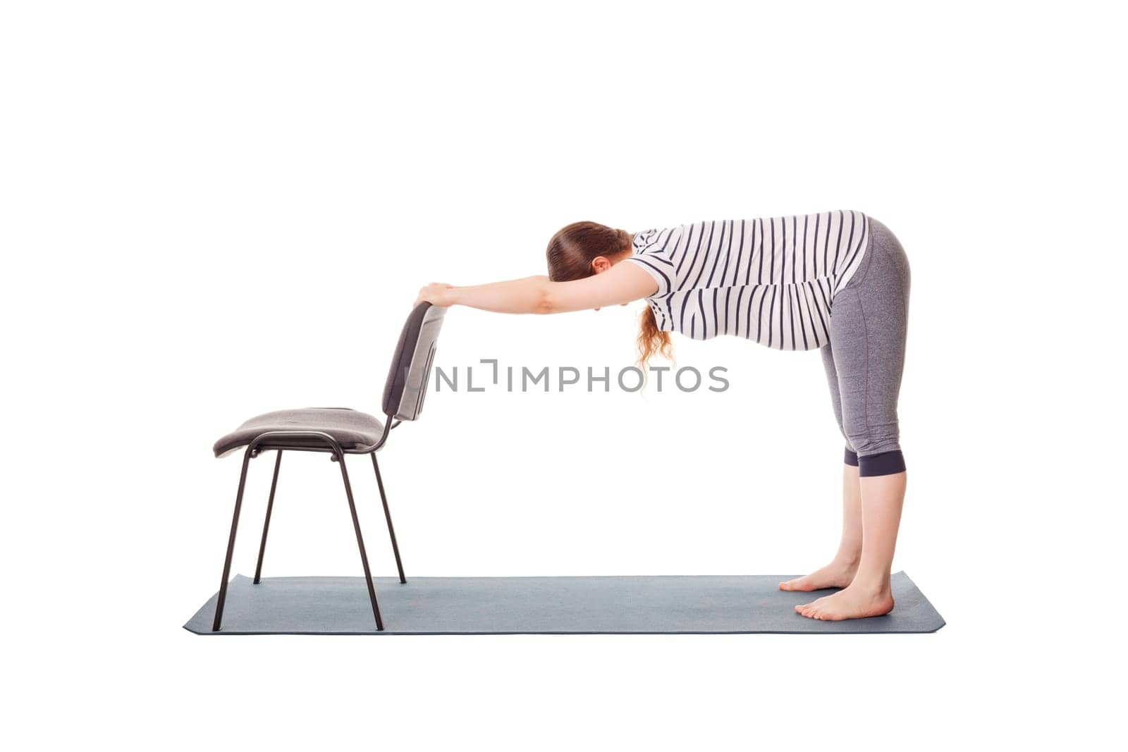 Pregnant woman doing yoga asana Uttanasana by dimol