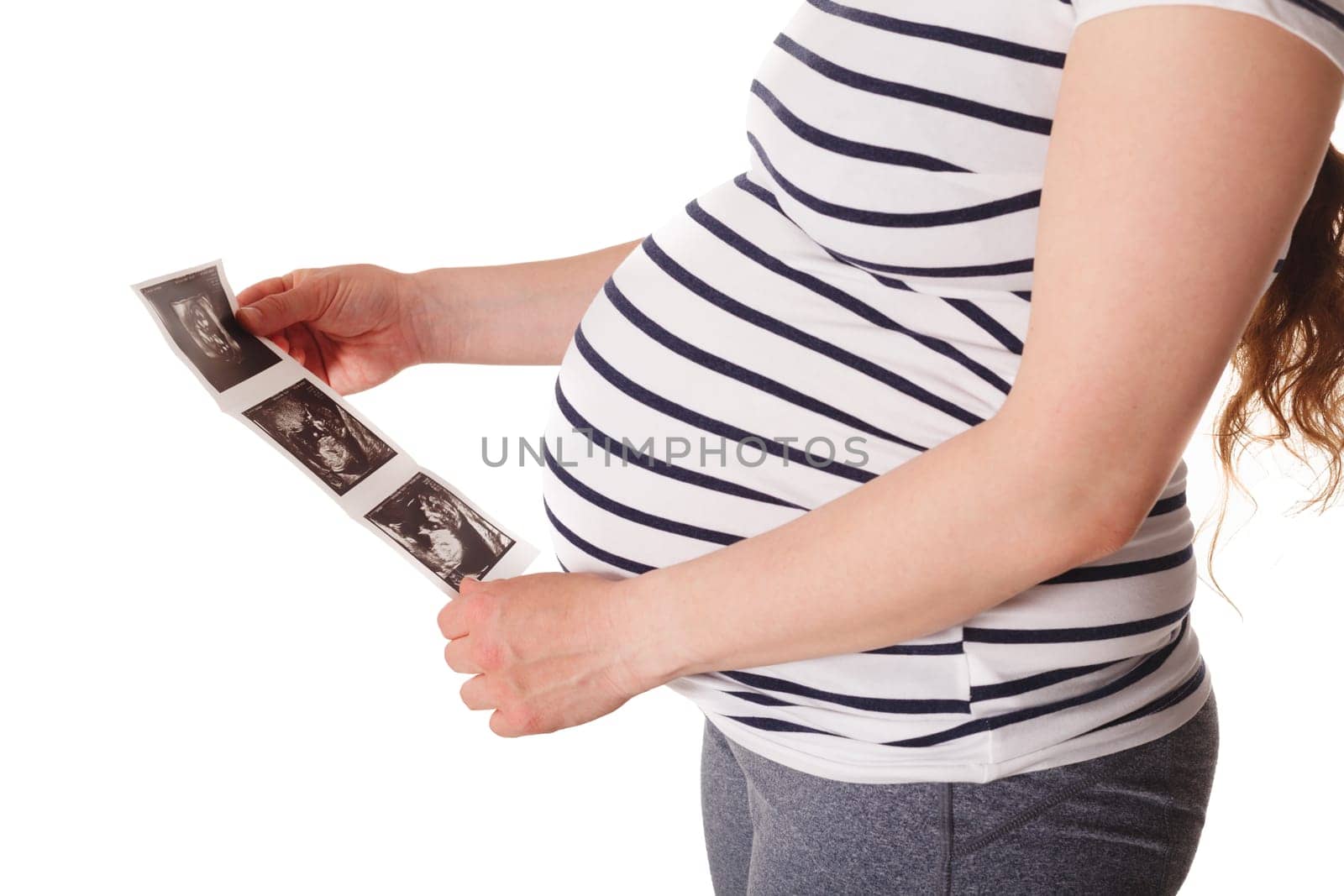 Pregnant woman standing and holding her ultrasound baby scan picture isolated on white