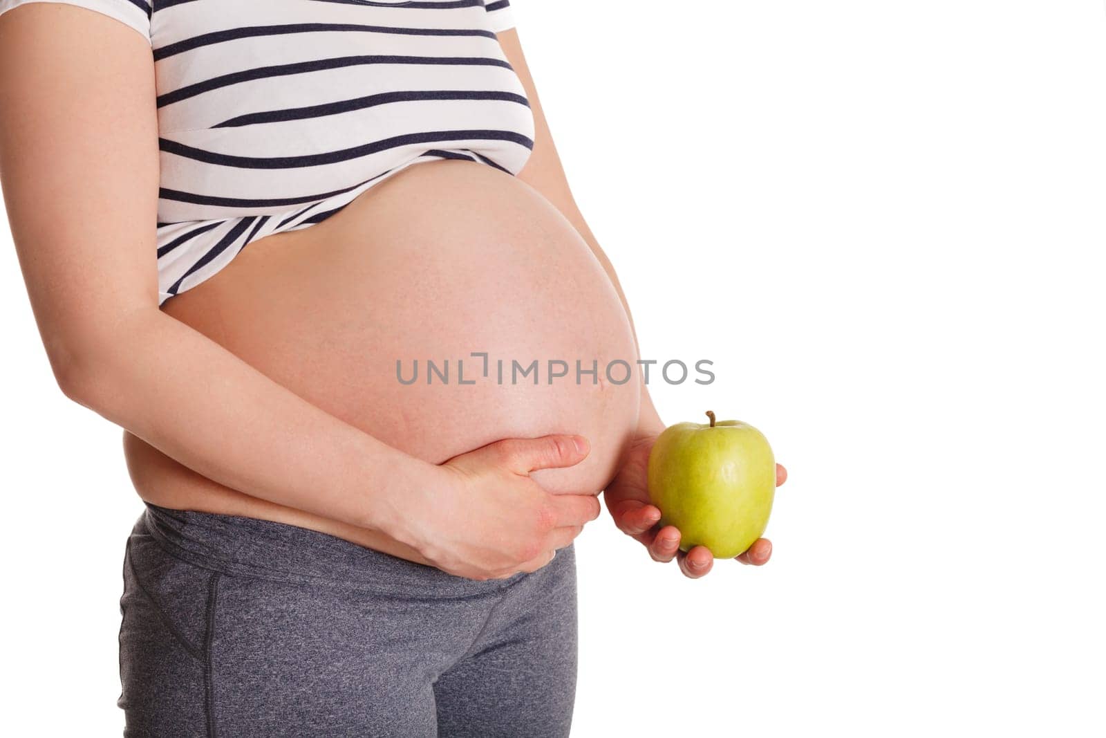Pregnant woman standing and holding apple near her stomach by dimol