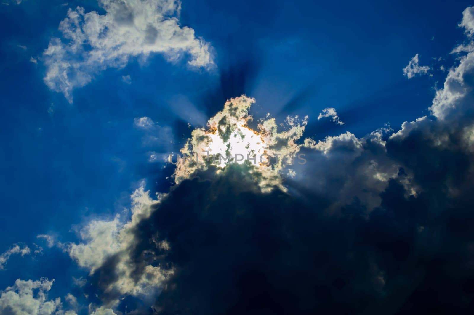 The sun rays break through a thundercloud on a blue sky. Sunbeam in heaven. Thunderclouds. Blue sky. Weather forecast. Climatic conditions. background image. Beautiful landscape.