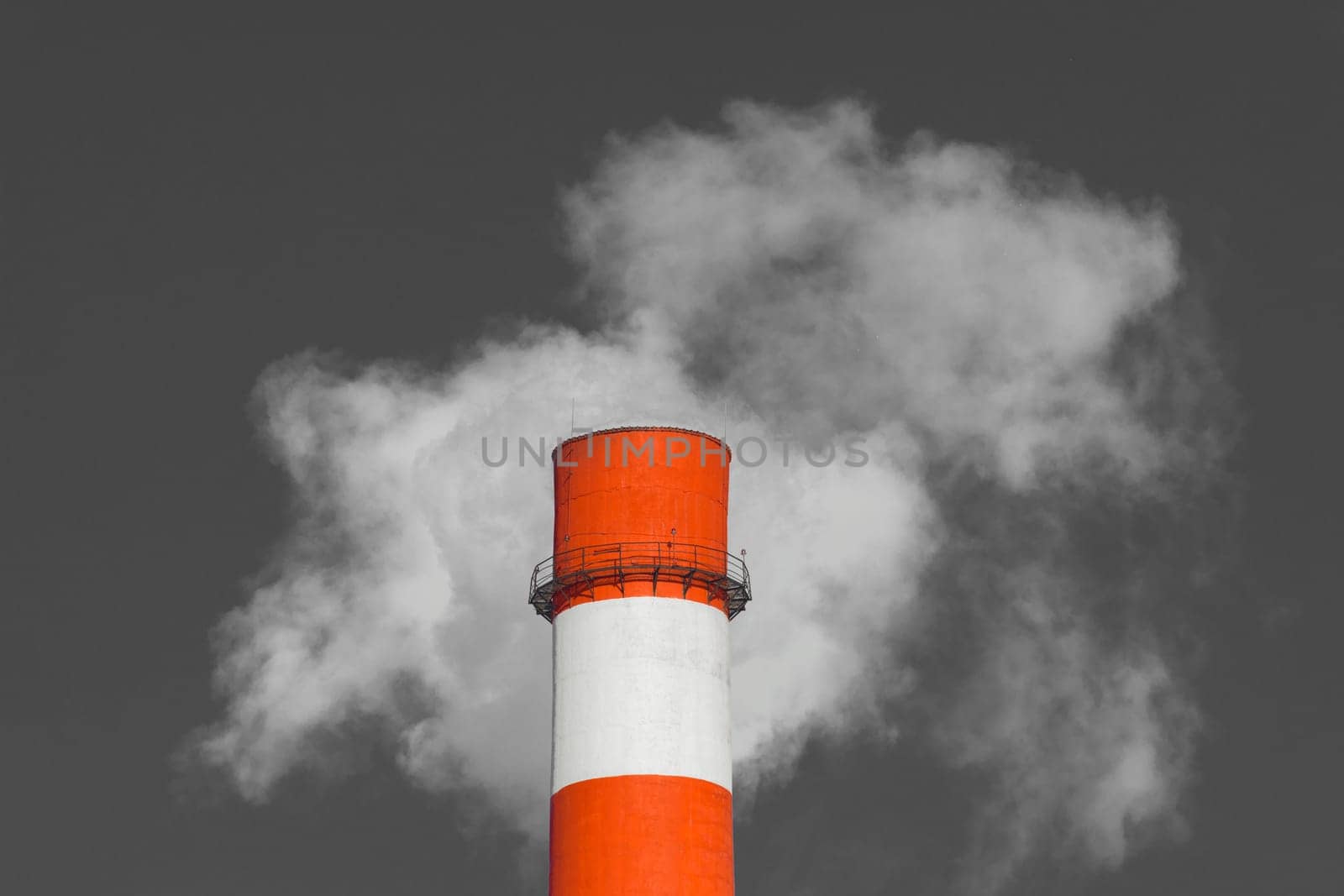 Pollution of the environment, ecology and air. Withdrawal of combustion products of soot, smoke and gases from the pipe of an industrial plant into the atmosphere against the background of a gray sky.