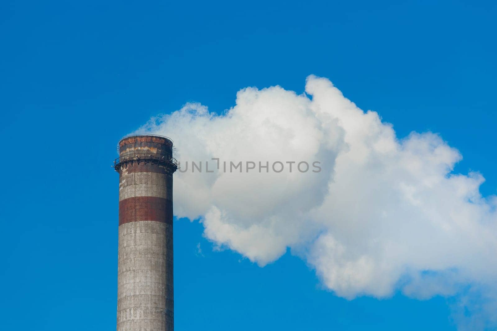 Pollution of the environment, ecology and air. Withdrawal of combustion products of soot, smoke and gases from the pipe of an industrial plant into the atmosphere against the background of a blue sky by AYDO8