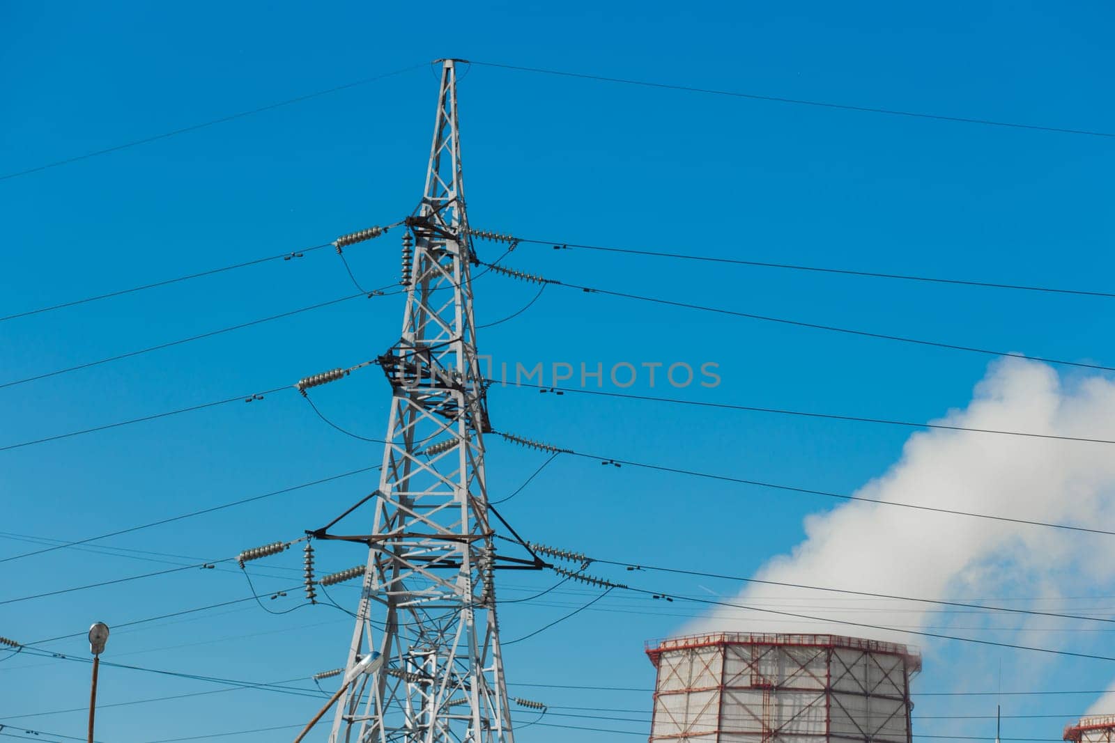 Smoke cooling tower pollution of the surrounding air environment of the atmosphere from the industrial plant and power lines high voltage tower.