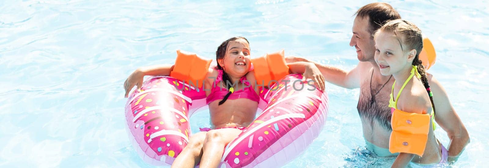 Active father teaching his children to swim in pool on tropical resort. Summer vacations and sport concept.