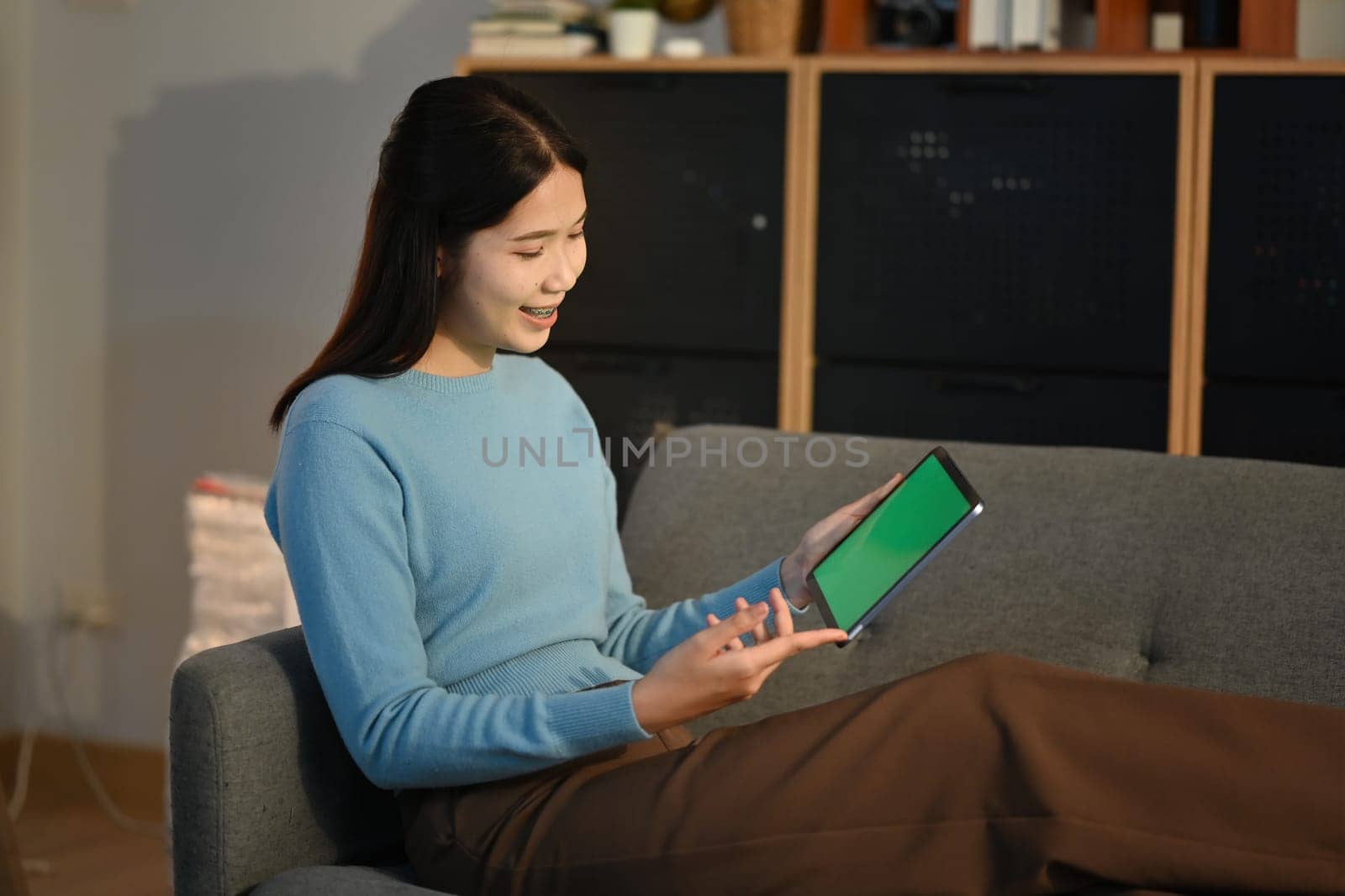 Young woman using tablet on sofa at home. by prathanchorruangsak